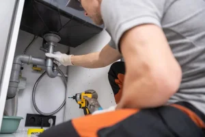 plumber unclogging drain underneath sink