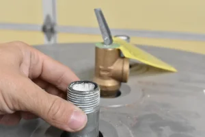 plumber inspects faulty pipe connection on water heater