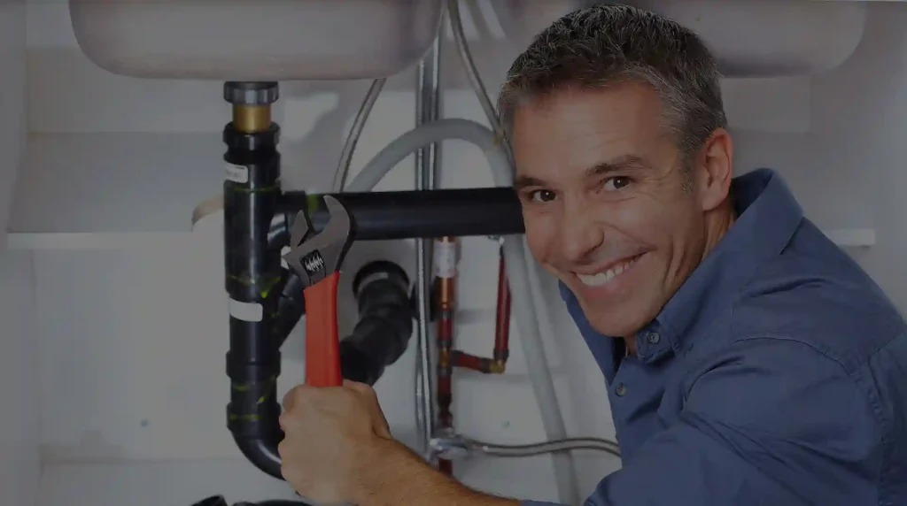 plumber inspects pipes under sink